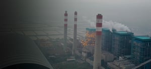 Large factory with large smokestacks and surrounding fields