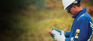 Technician wearing safety equipment looking at a seismometer