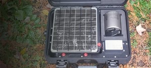 Open deploy kit on the ground showing the solar panel and seismometer in their slots