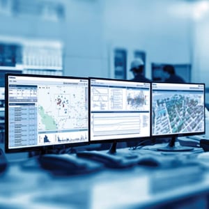 Three computer monitors displaying nanometrics software dashboards