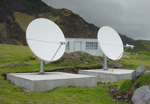 Two communication dishes set on large concrete pads in a mountain region