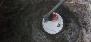 Trillium compact seismometer sitting in a posthole in the earth connected to a large cable