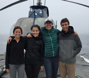 Four staff members arm in arm in front of a helicopter