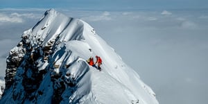Scientists on the peak of the mountain with clouds in the background