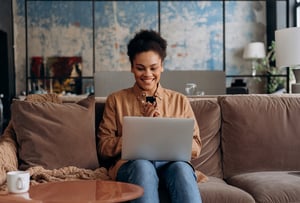 Woman working on a laptop while sitting on her couch